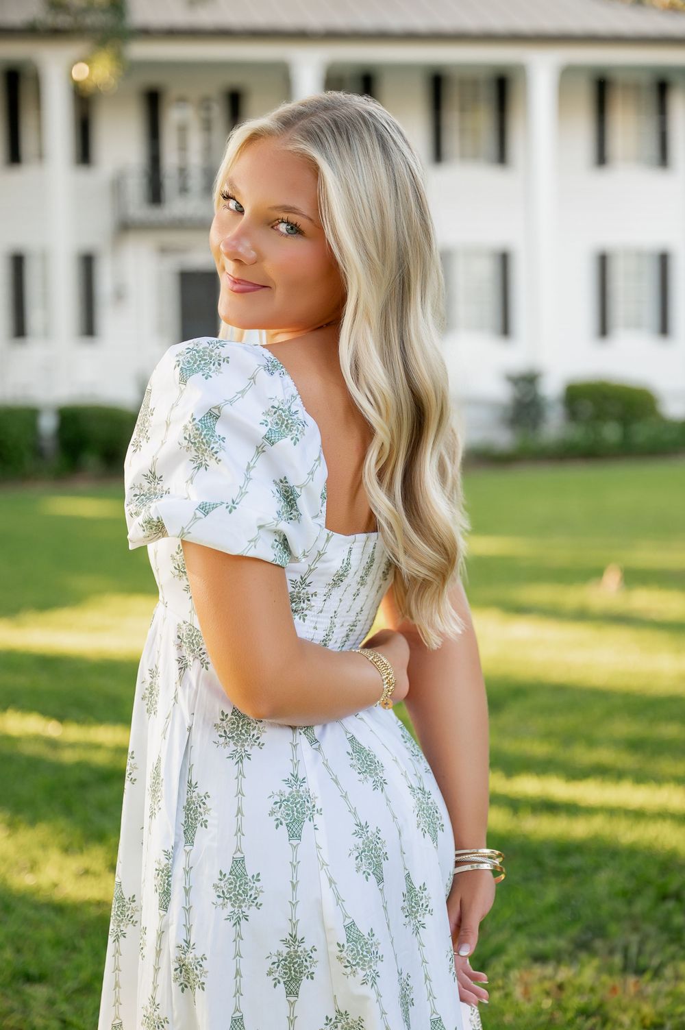 Summer portrait session in front of white colonial style building with manicured lawn.