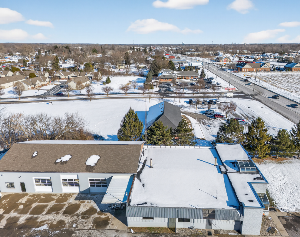 Aerial winter view of brick and white commercial buildings near a suburban road.
