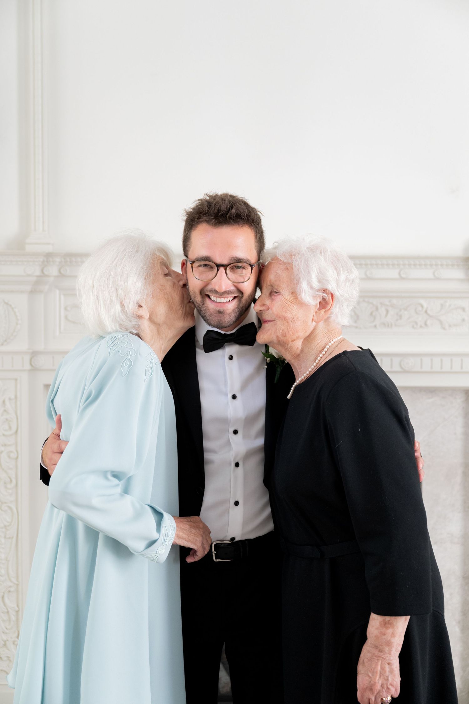 Three candid photos showing joyful moments between people in formal attire against a white backdrop.
