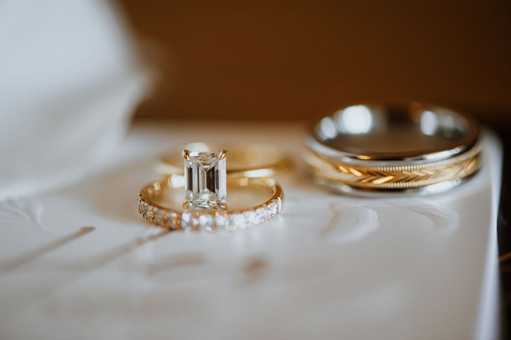 Close-up macro shot of elegant diamond wedding rings on a reflective surface with warm lighting.