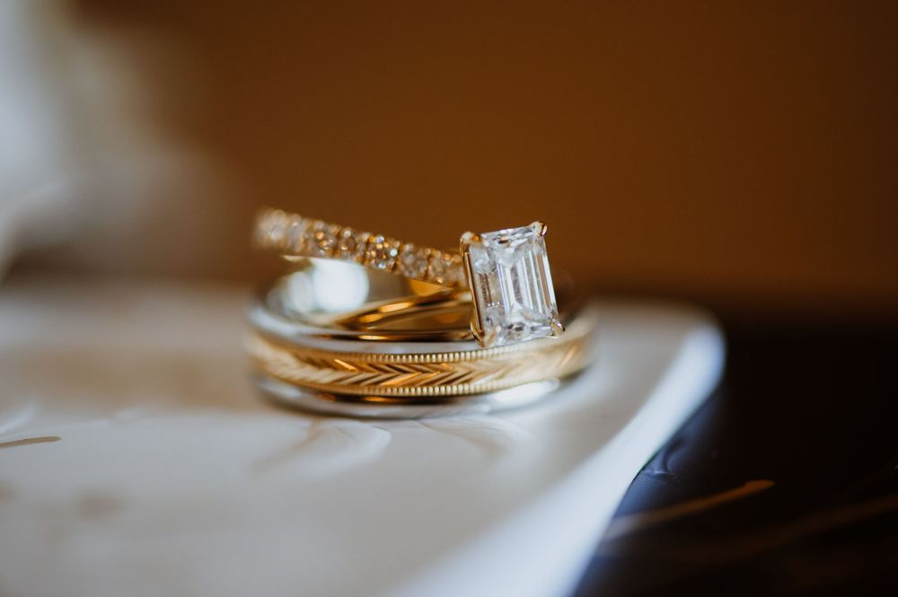 Close-up detail of wedding rings resting on a reflective surface with soft lighting and shallow depth of field.