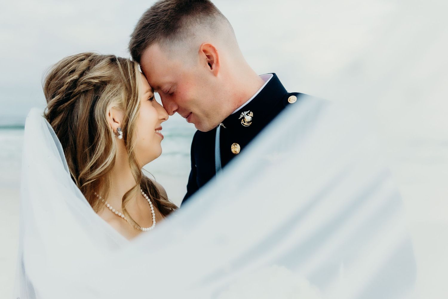 A romantic wedding couple shares an intimate moment against a bright white background.