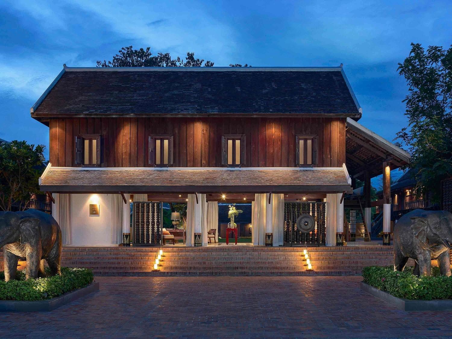 Modern wooden house exterior with warm lighting at dusk showcases contemporary architectural design and landscaping.