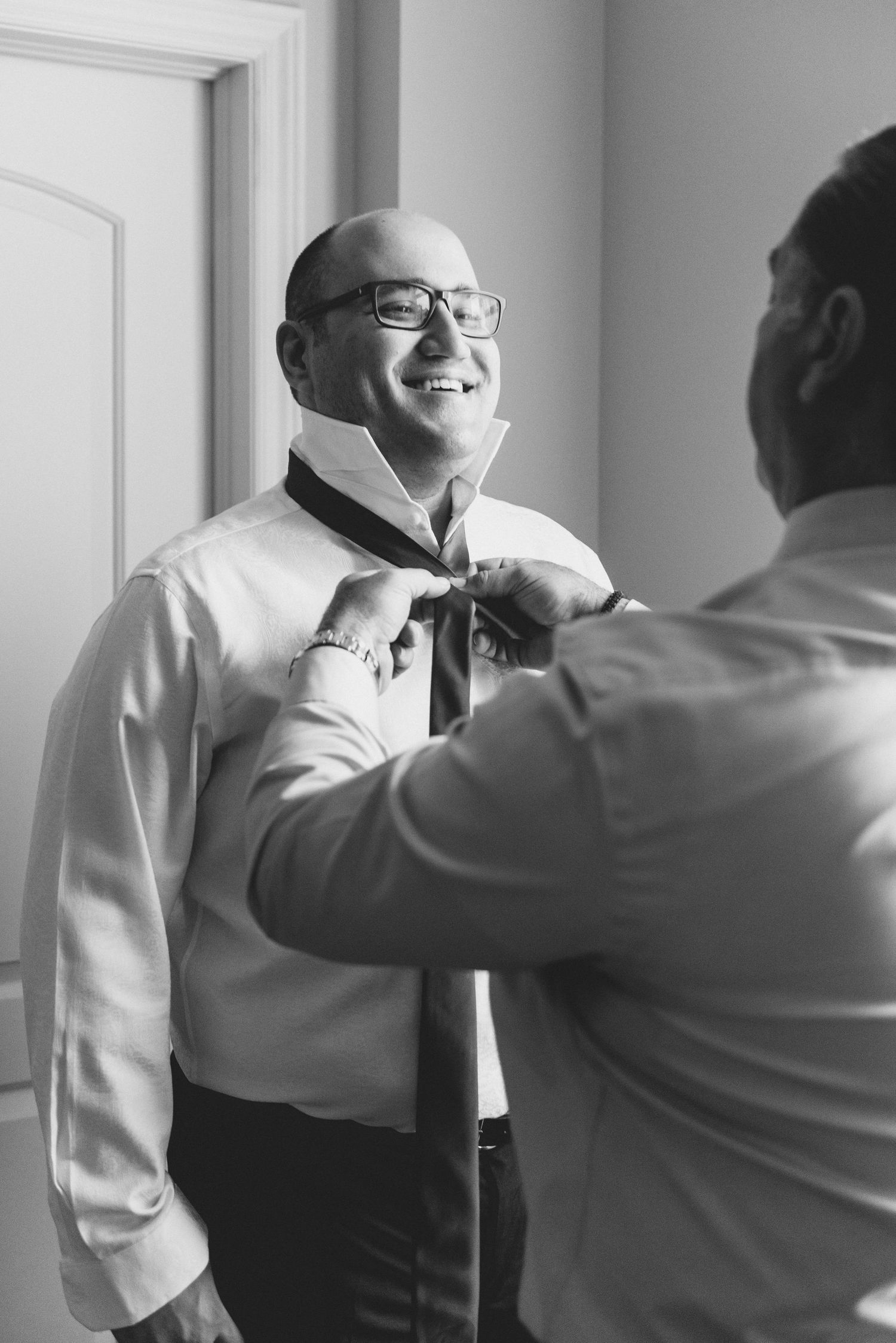 A series of black and white photos showing a person helping another adjust their tie and collar.