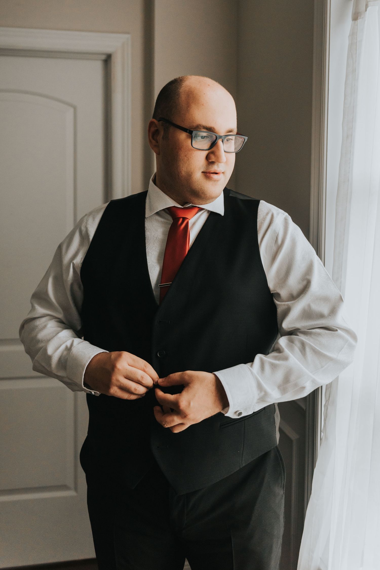 A person in a black vest and white shirt getting dressed by a window in a series of connected photos.
