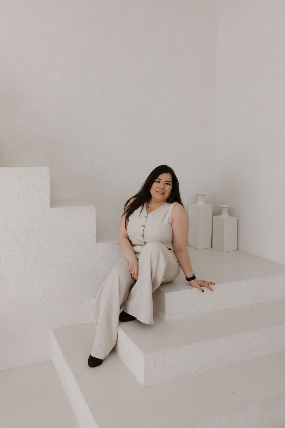 Woman in light-colored outfit reclines on white architectural steps.