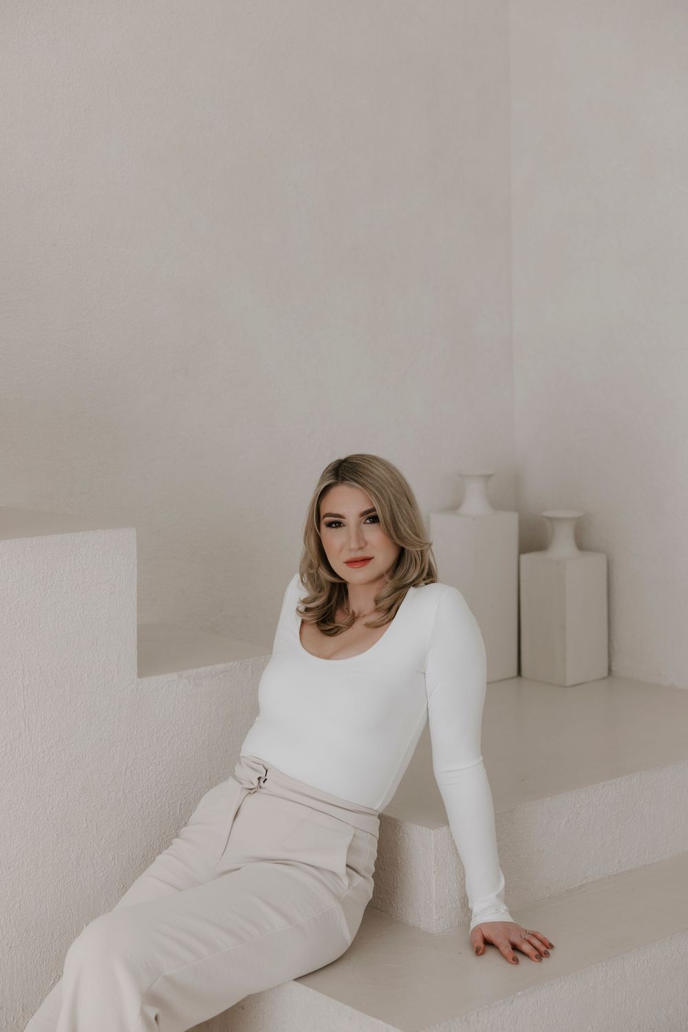 Fashion photography series featuring white outfit against neutral backdrop with decorative vases.