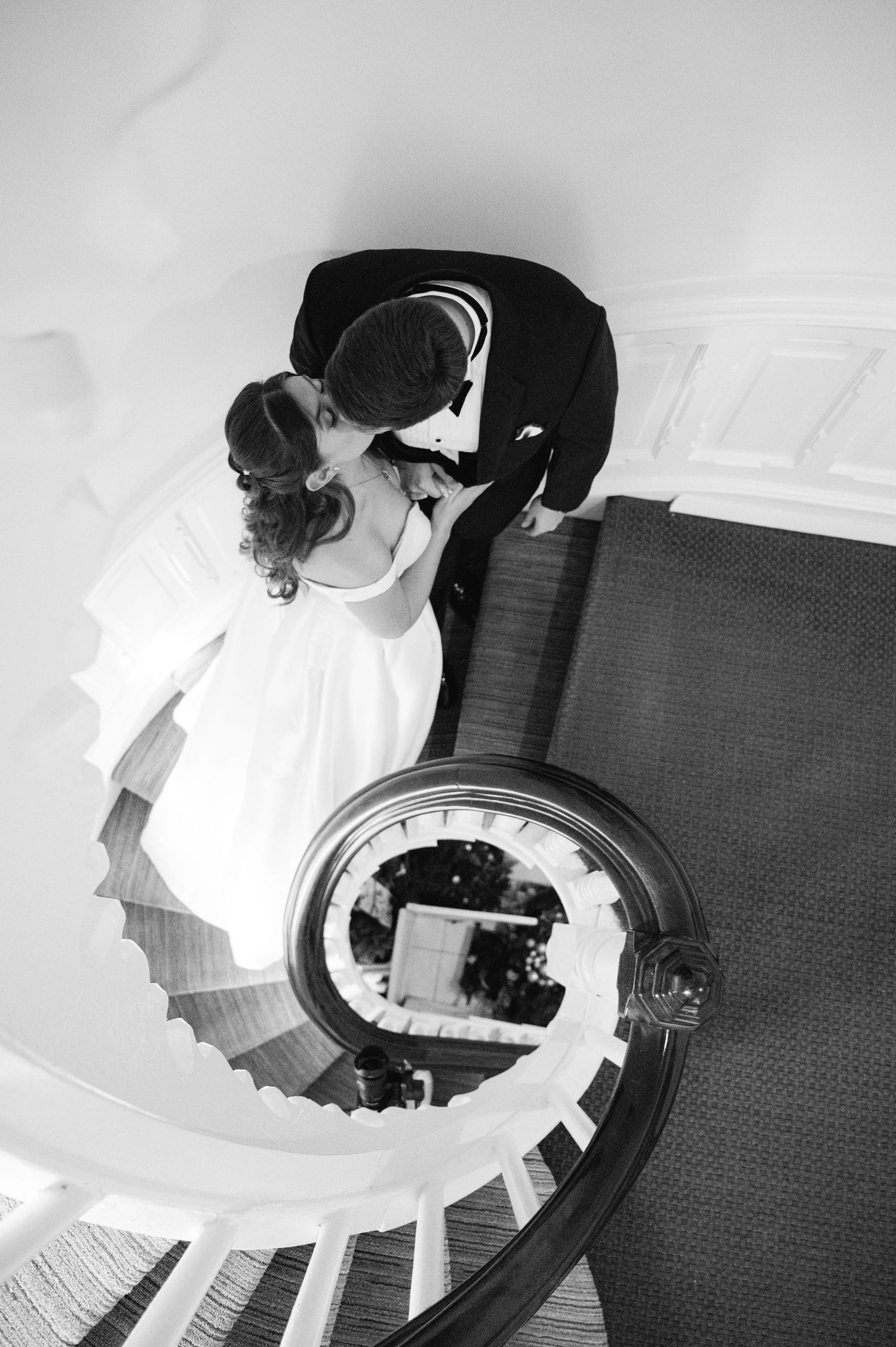 A creative black and white photo of newlyweds kissing on a spiral staircase taken by Westchester wedding photographer at the Whitby Castle.