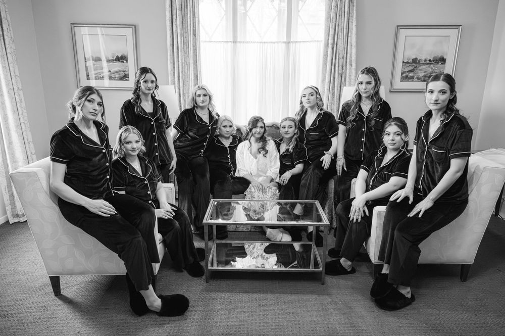 Bridesmaids pose seriously while wearing matching black pjs while getting ready together before a wedding at the Whitby Castle.