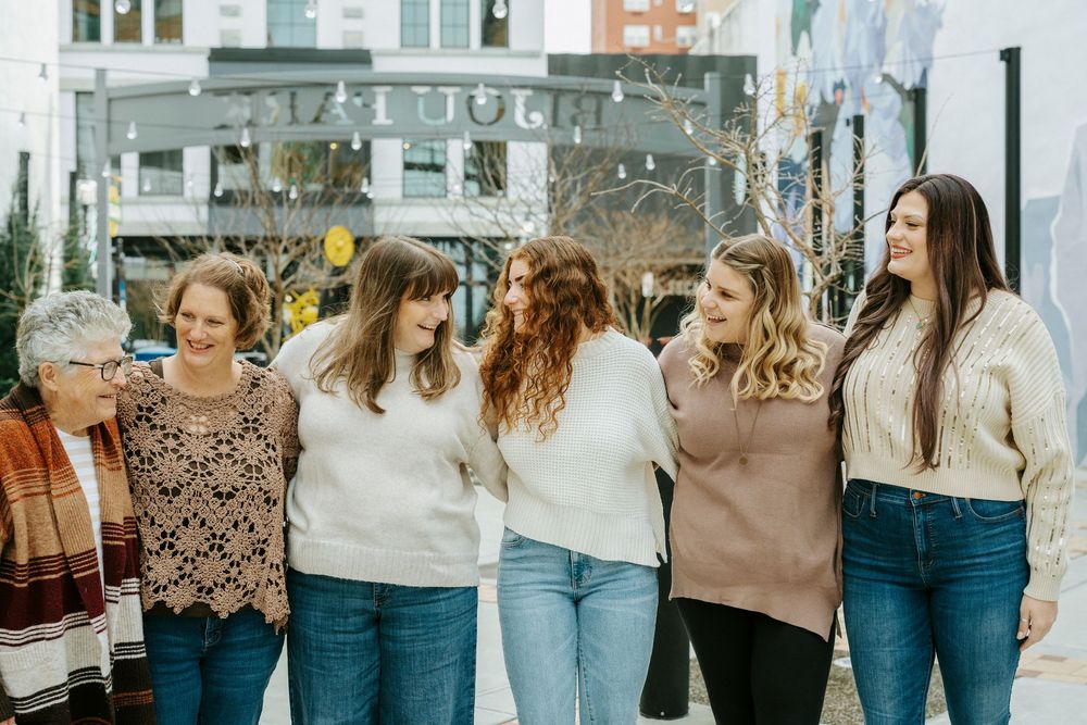 Group of friends in casual outfits walking together outdoors while holding brown paper shopping bags.