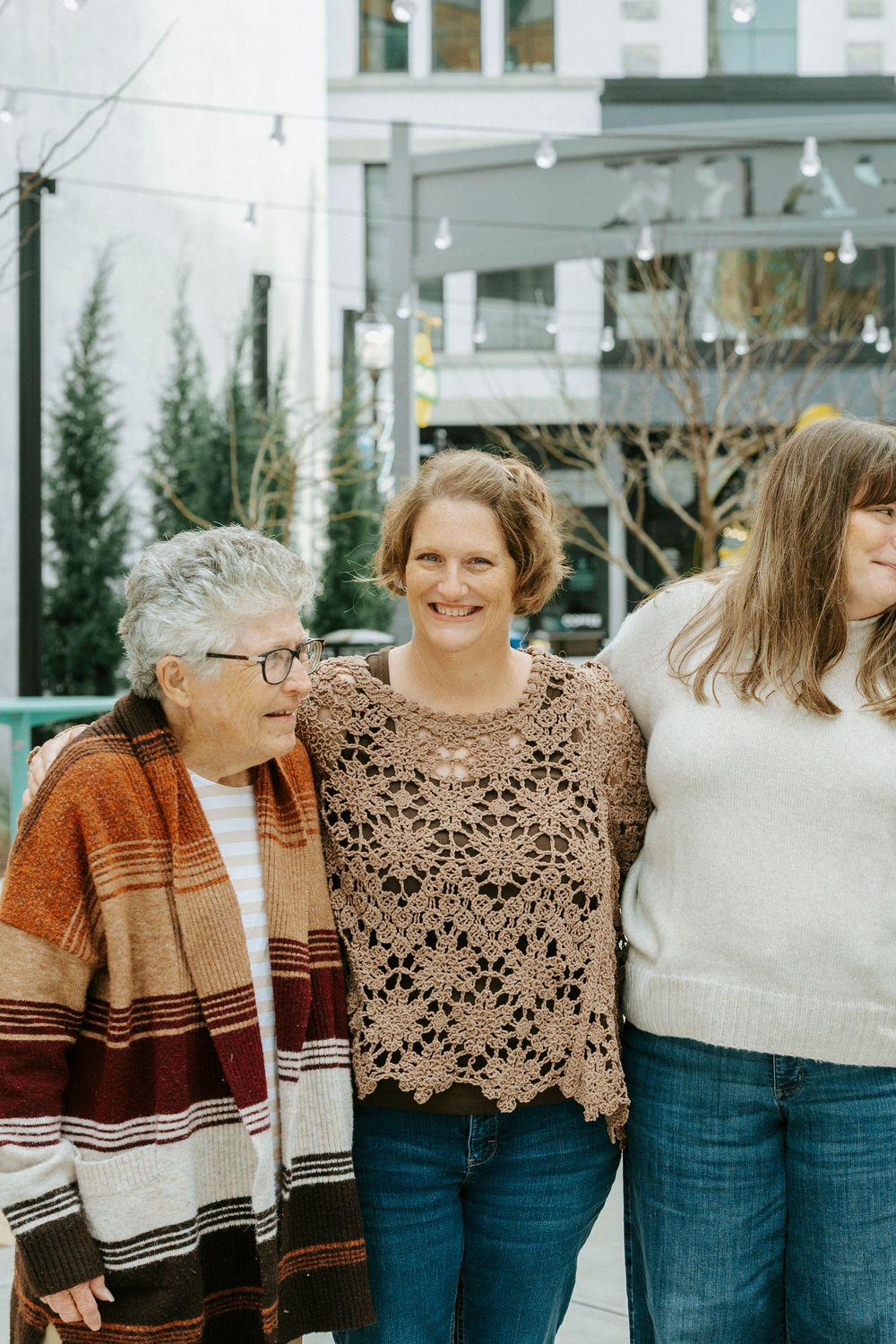 A group of women in cozy sweaters stand together smiling in casual winter outfits.