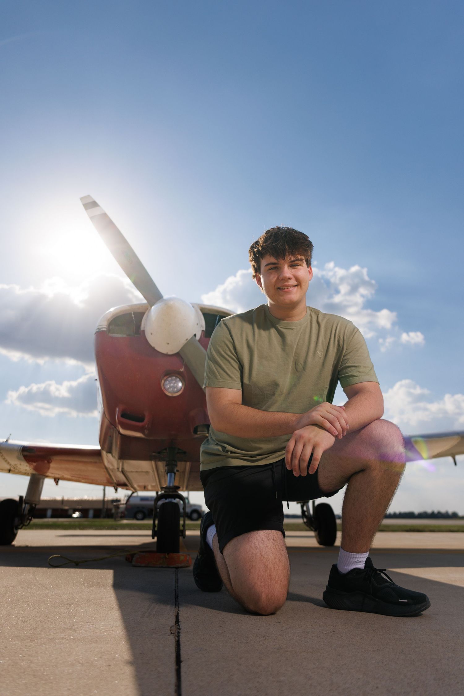 A sequence of four photos showing someone sitting on an airport runway next to an aircraft in bright sunlight.
