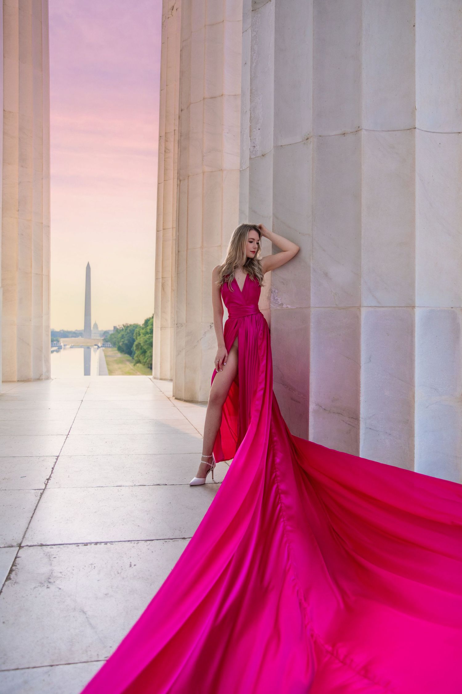 A stunning red gown with a dramatic flowing train photographed at the Lincoln Memorial with the Washington Monument visible.