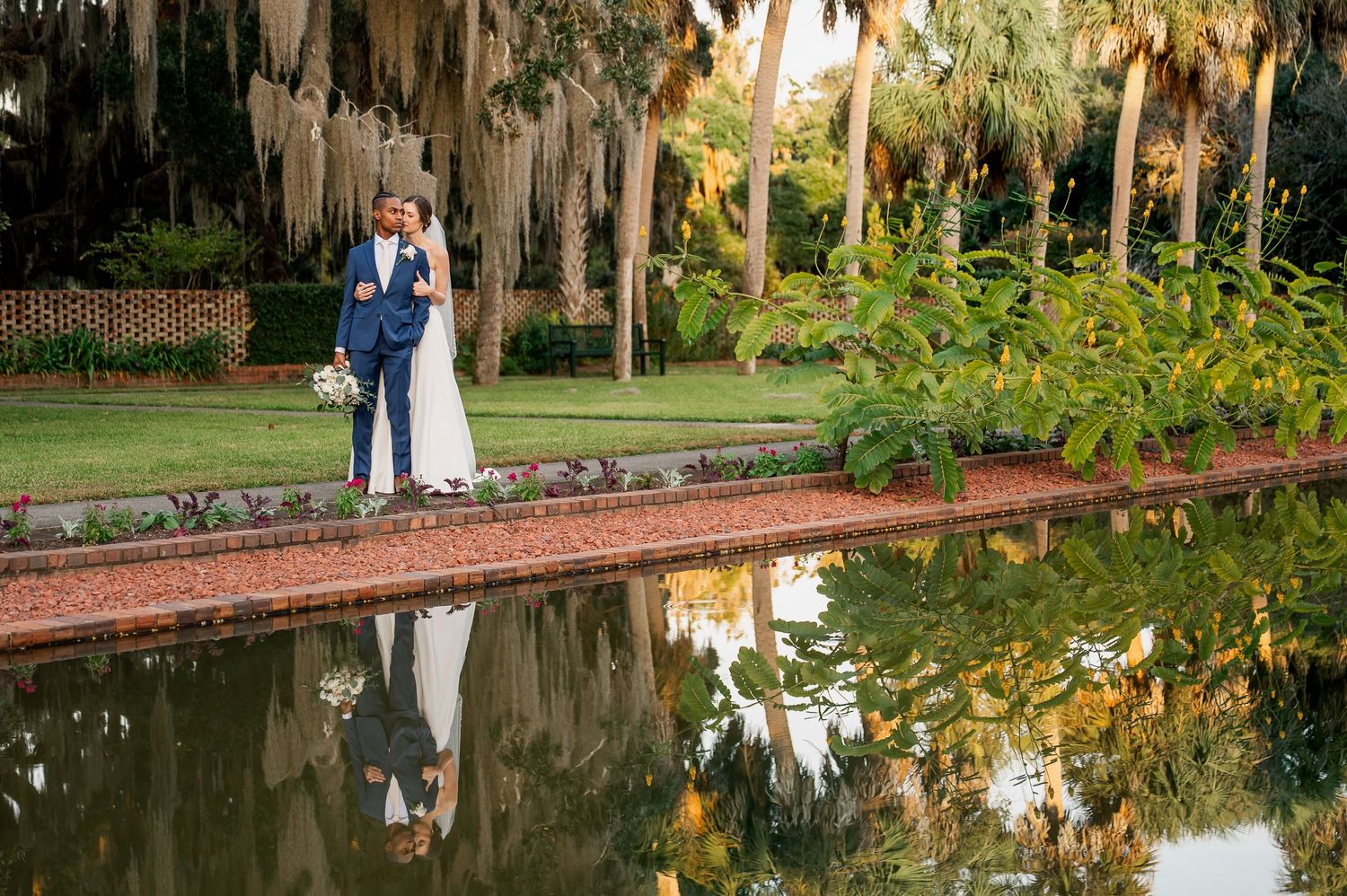 Wedding couple reflected in still water with Spanish moss trees creating a romantic atmosphere.