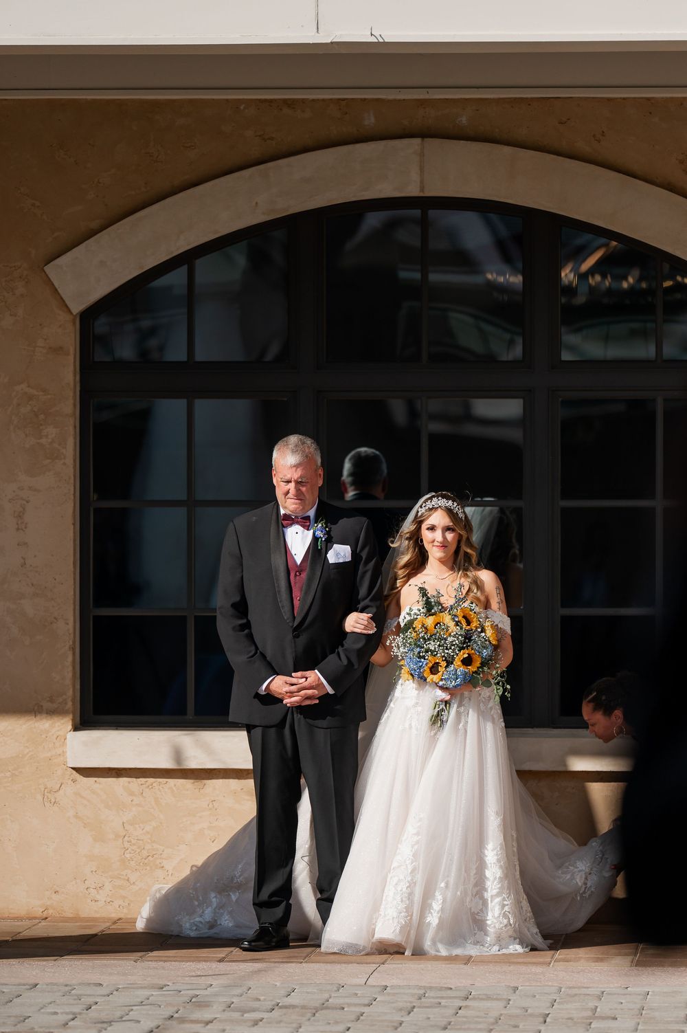 Bride and escort walking down covered outdoor walkway before ceremony.
