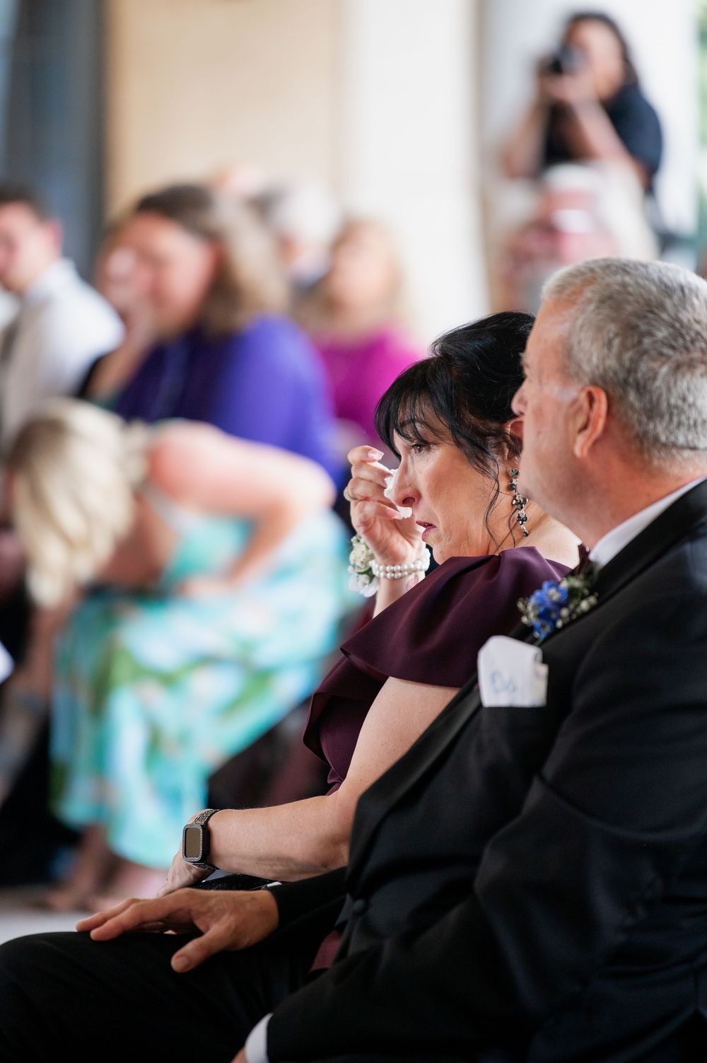Wedding guests seated in formal attire watching emotional ceremony.