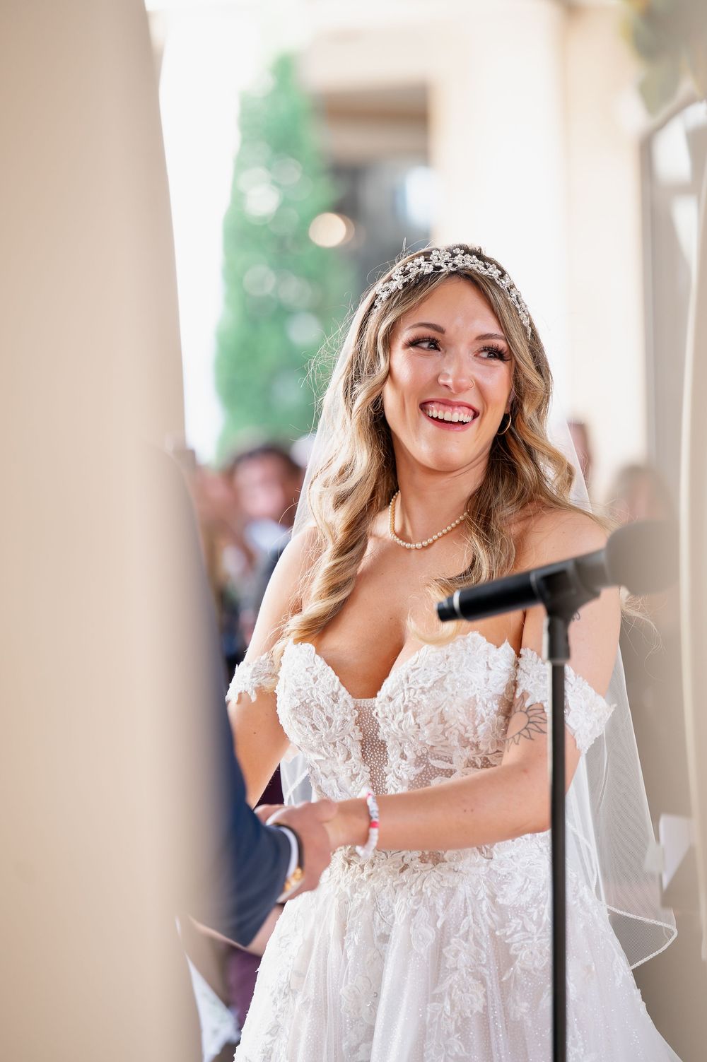 Bride in lace wedding dress smiling joyfully during wedding celebration.