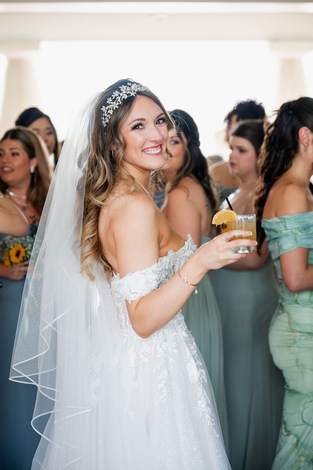 A bride in a sparkly white gown celebrates with bridesmaids wearing mint green dresses.