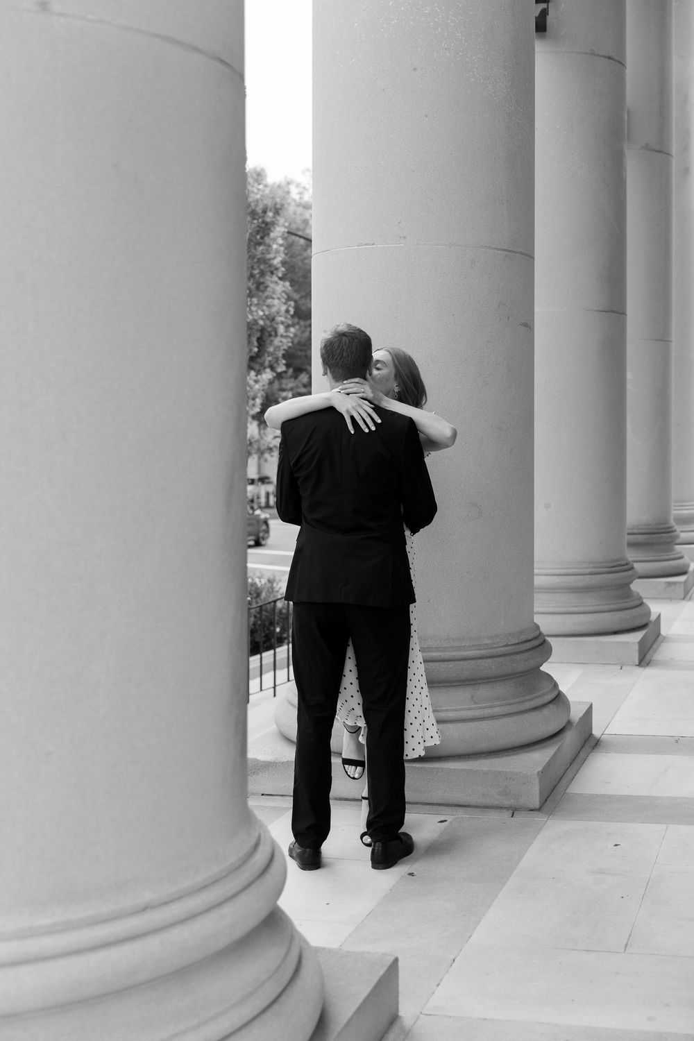 A sequence of black and white photos showing two people embracing between classical white columns.
