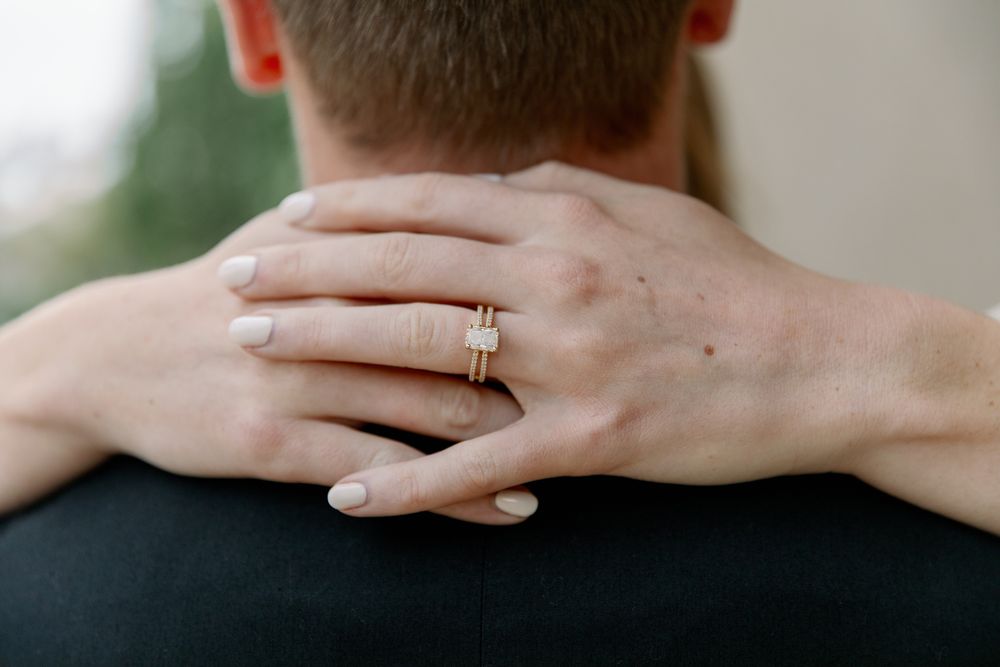 A close-up view of hands wearing wedding rings against a soft blurred background.