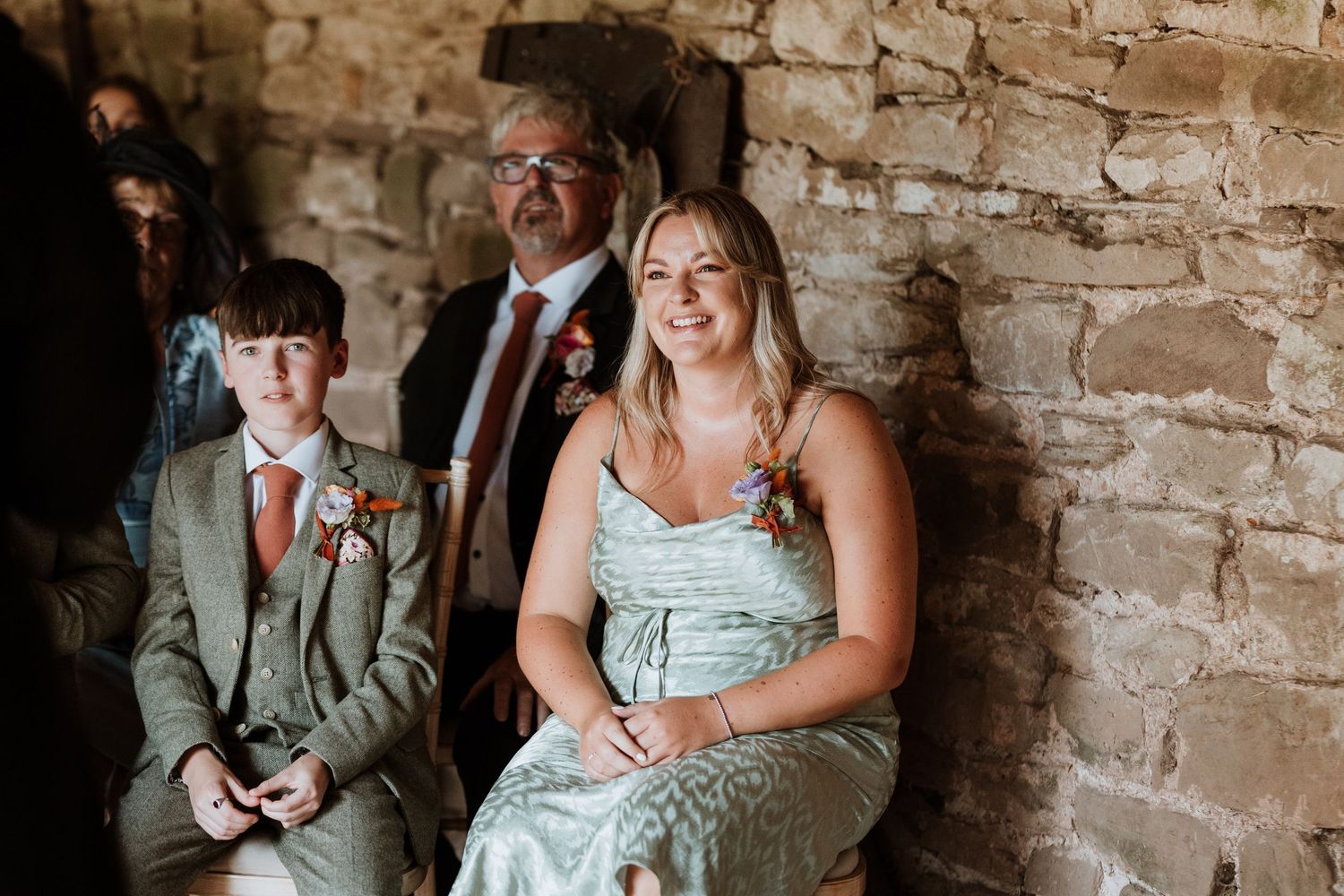 Wedding guests sit and socialize in a rustic brick-walled venue during a celebration.