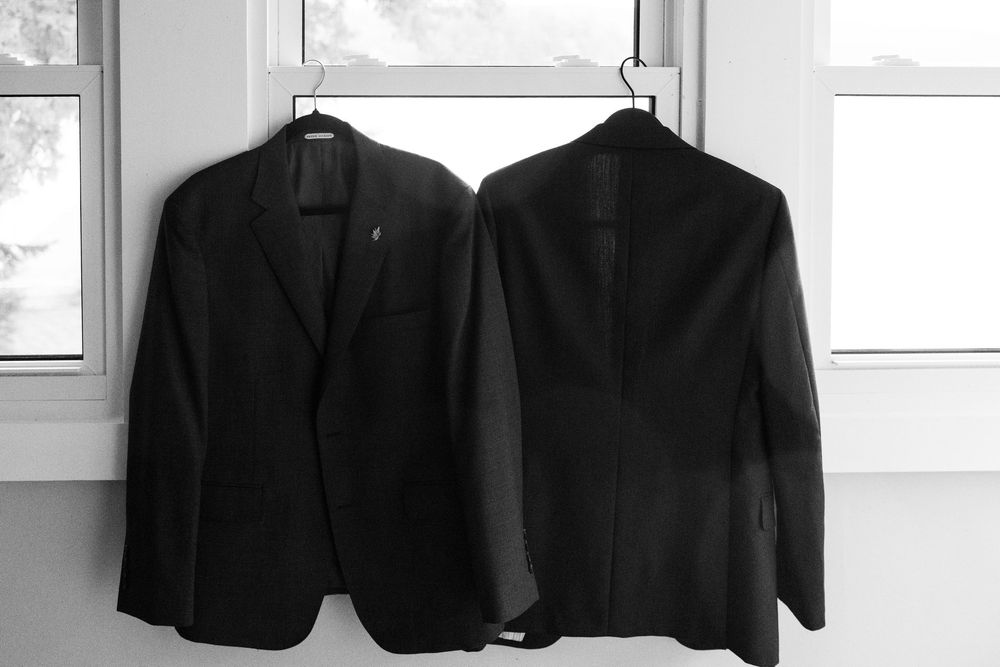Black formal jackets hanging in a bright white room with windows.