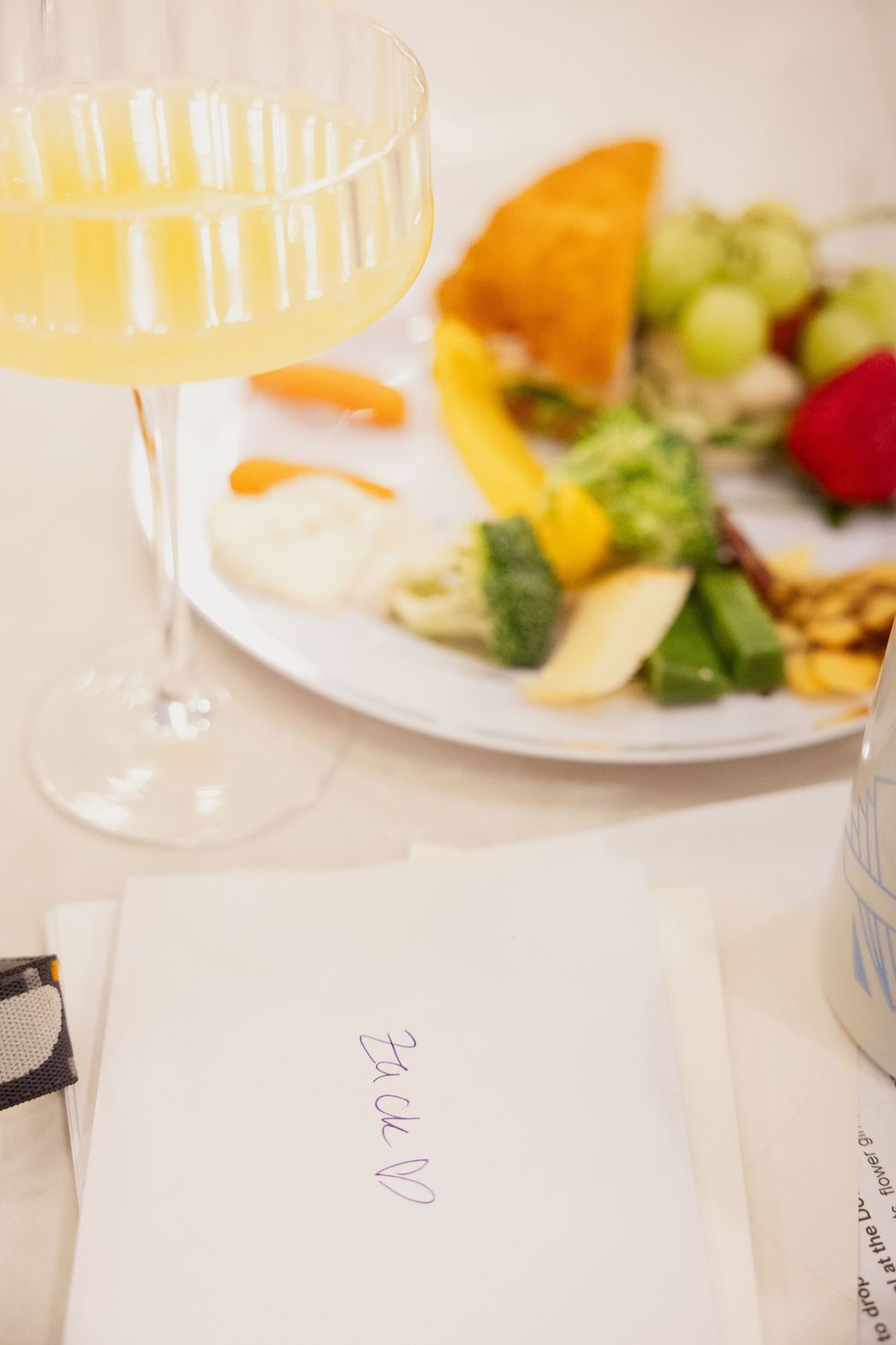 Place settings with wine glasses and colorful fruit plates on a white tablecloth.