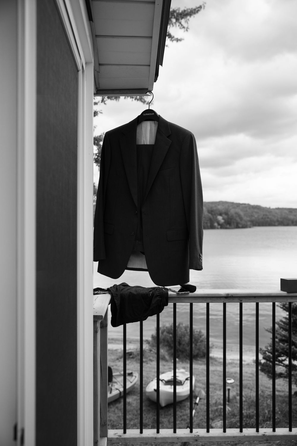 Black suit jackets hanging on a porch railing with a scenic mountain view in the background.