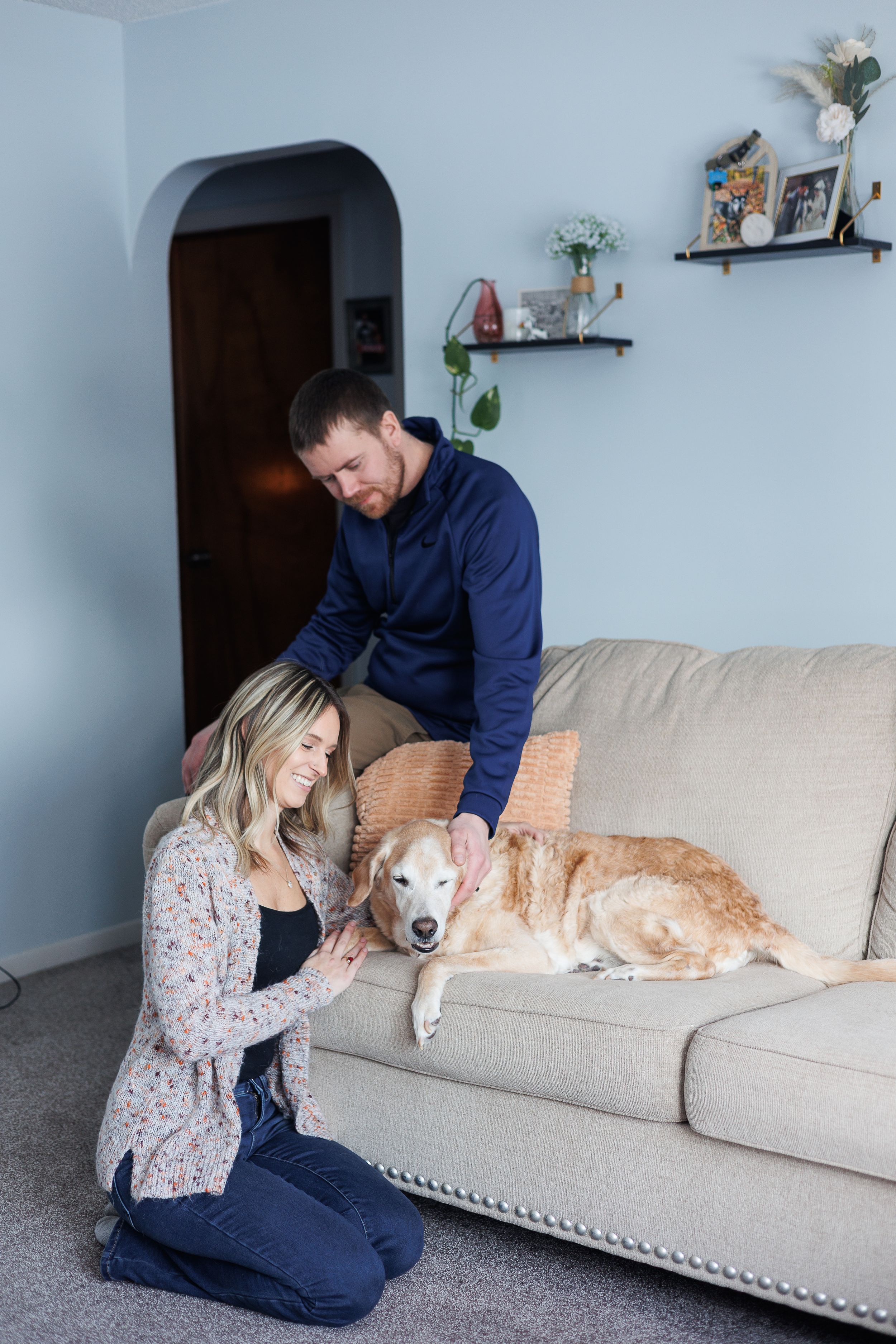 Family and dog relaxing together on gray couch in cozy home setting.