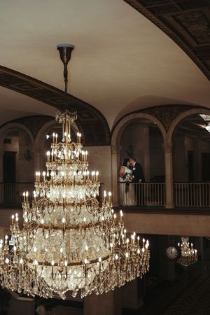 Elegant crystal chandeliers hanging in a grand ballroom with arched architecture.