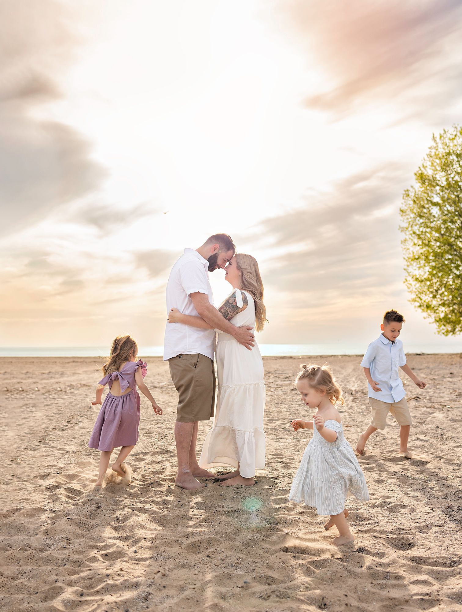 Family playing together on a sandy beach at sunset creating joyful memories.