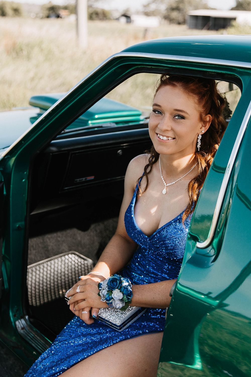 Graduate girl sitting in a car at formal photo shoot