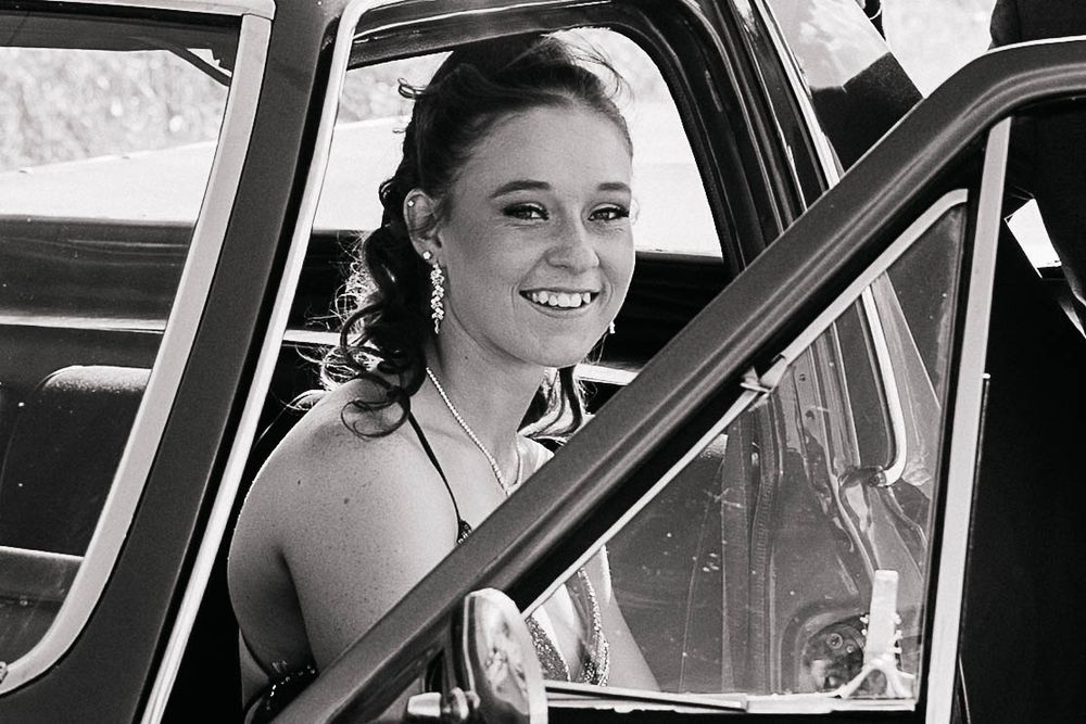 Graduate girl sitting in a car at formal photo shoot