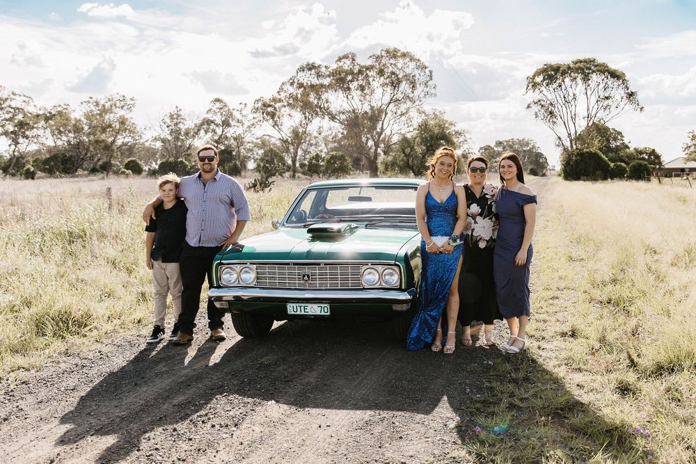 Family standing around a green car at formal photo shoot