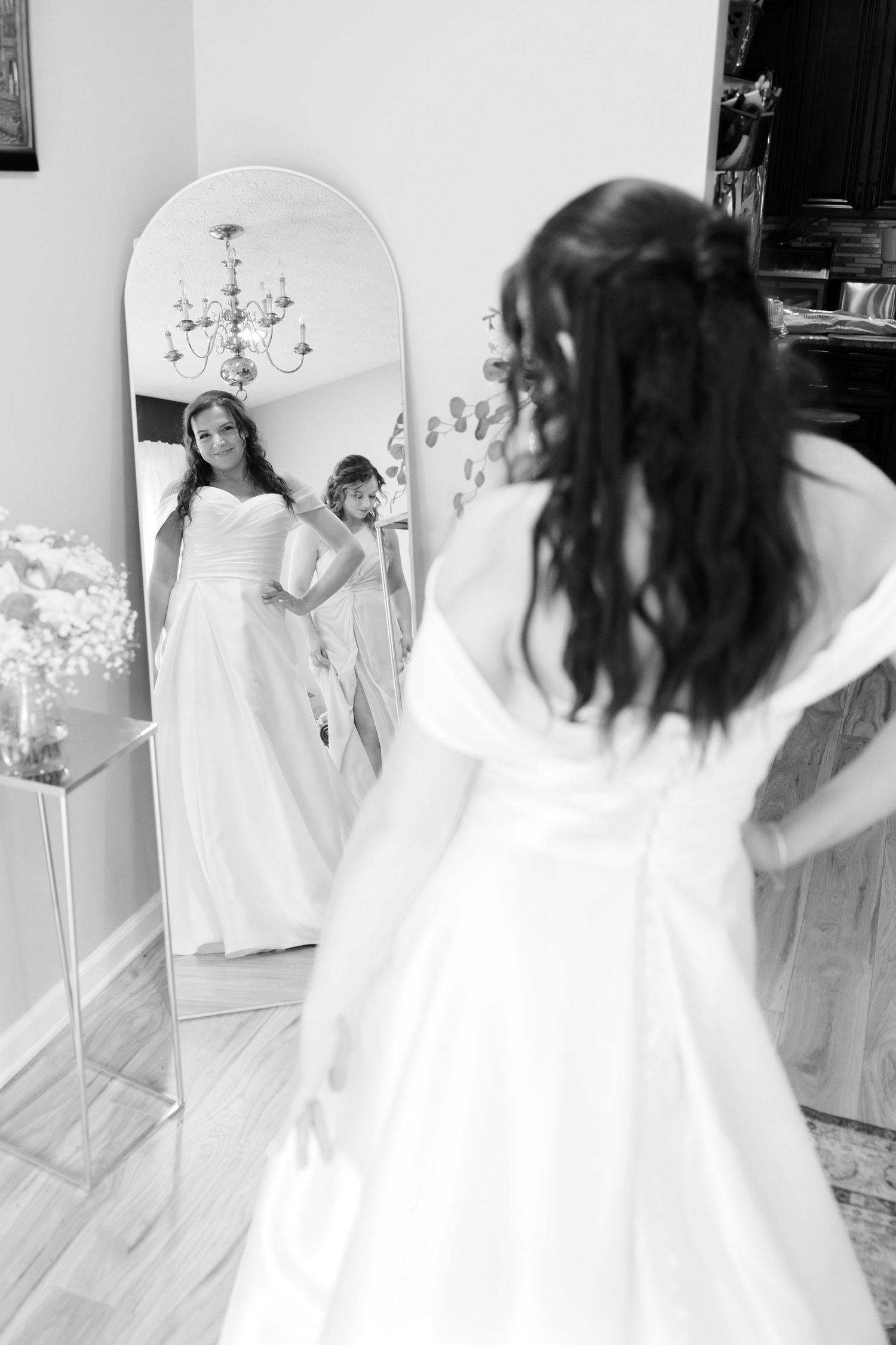 Bride looking in large mirror before wedding.