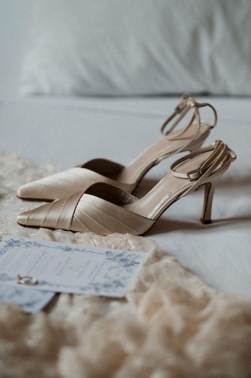 Elegant beige satin wedding shoes with low kitten heels displayed on a light textured surface.