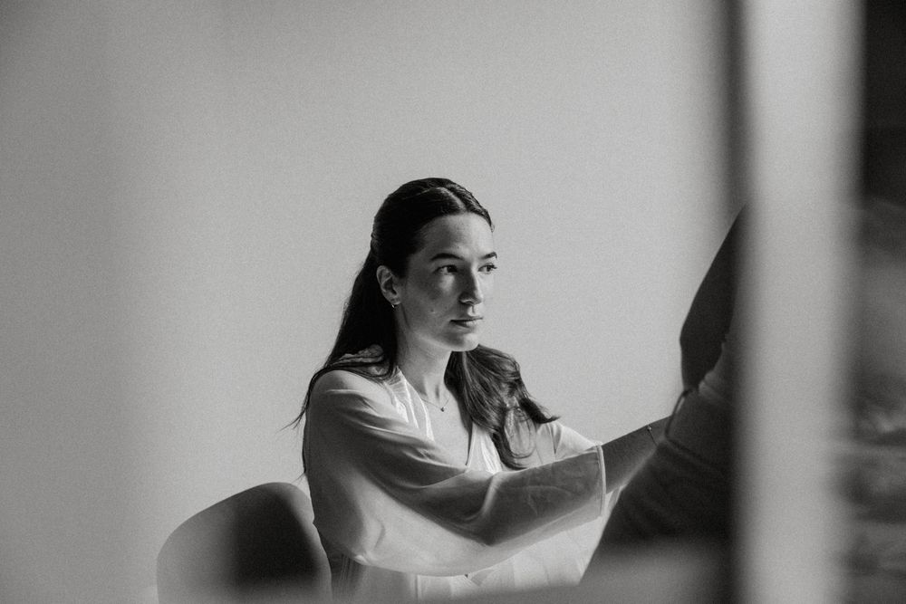 Person in casual attire reading a book while sitting near a window with natural light streaming in.