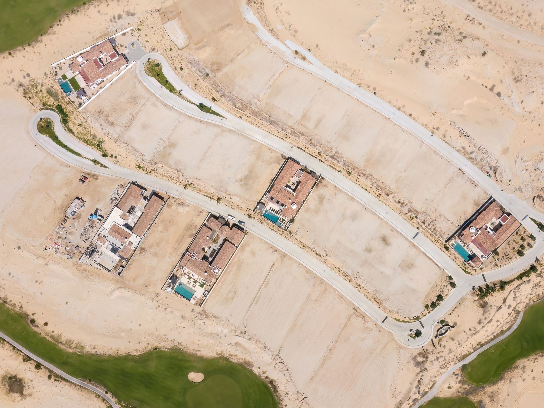 Aerial view of desert development showing construction sites, roads, and scattered buildings in an arid landscape.