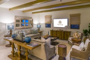 Modern coastal living room with exposed wooden beams and comfortable seating arranged around entertainment area.