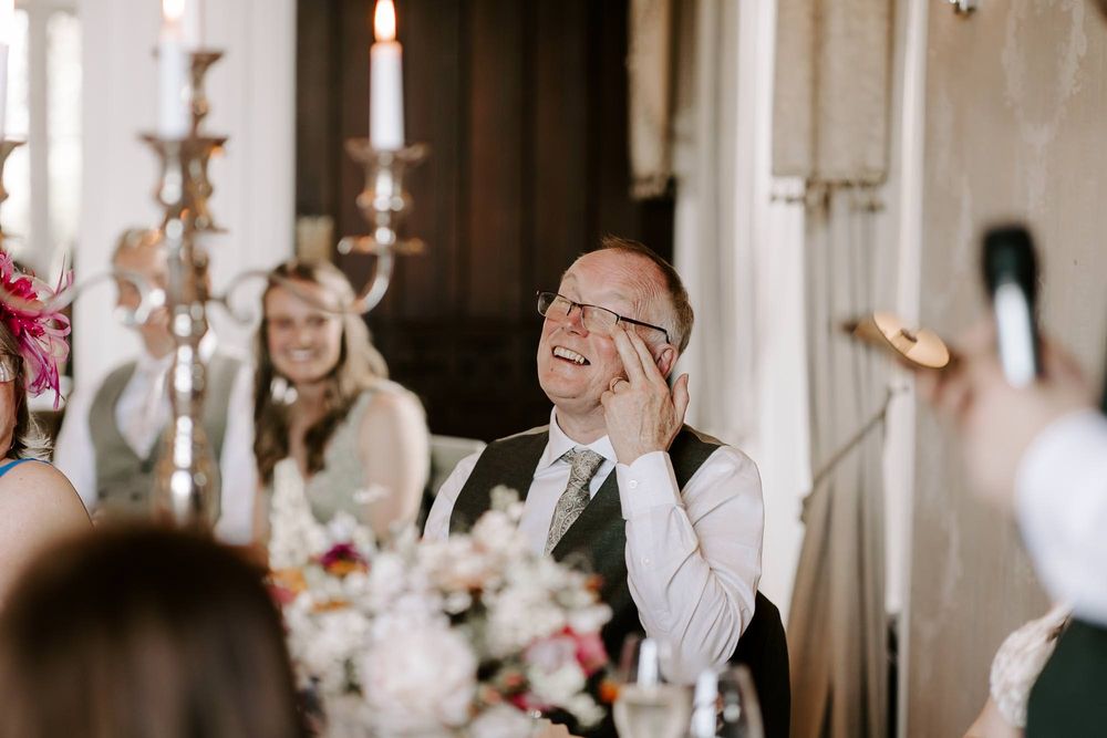 An emotional moment at an elegant wedding reception with candlelight and pink floral centerpieces.