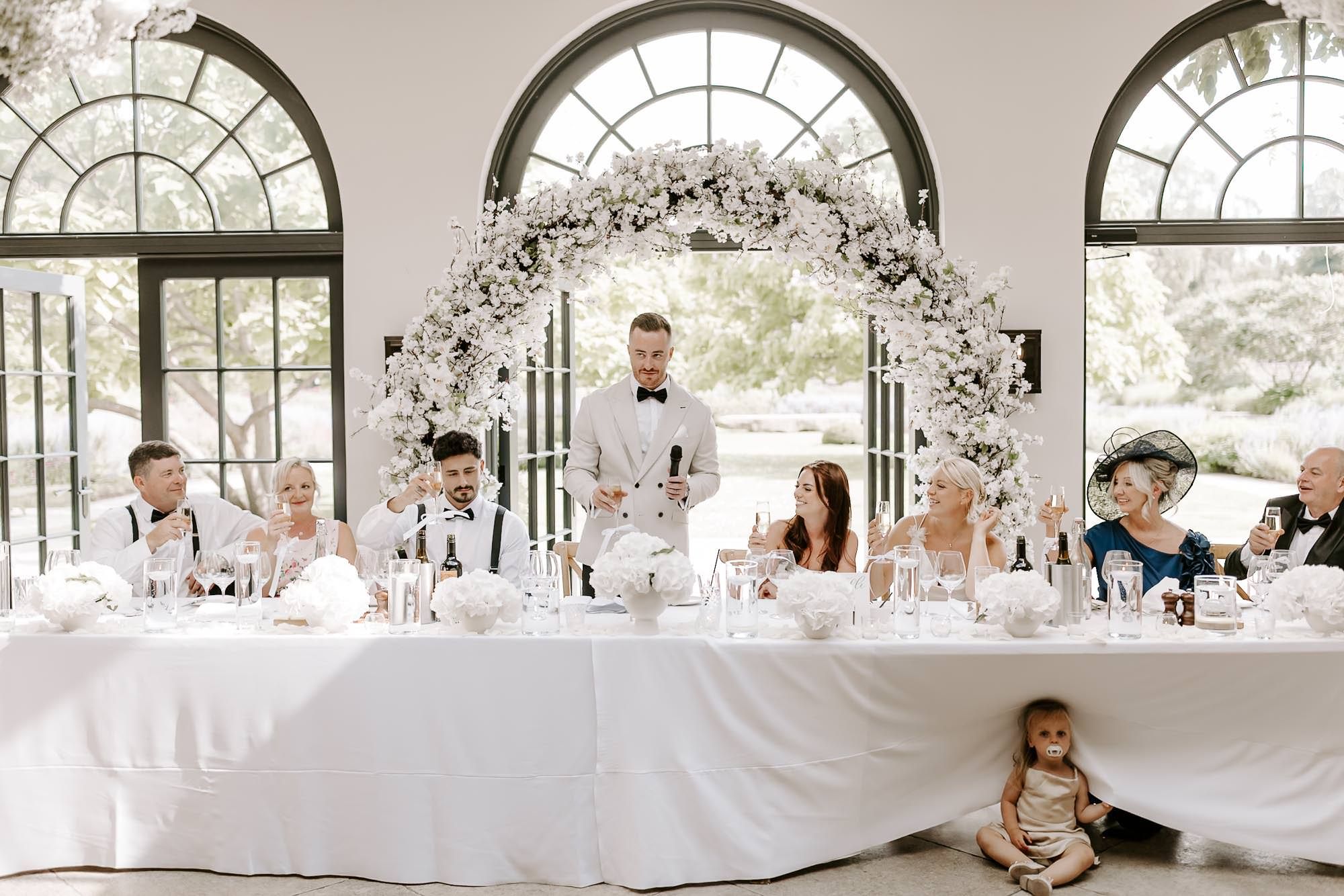 A panoramic collage of elegant wedding reception venue with white decor and floral arrangements under arched windows.