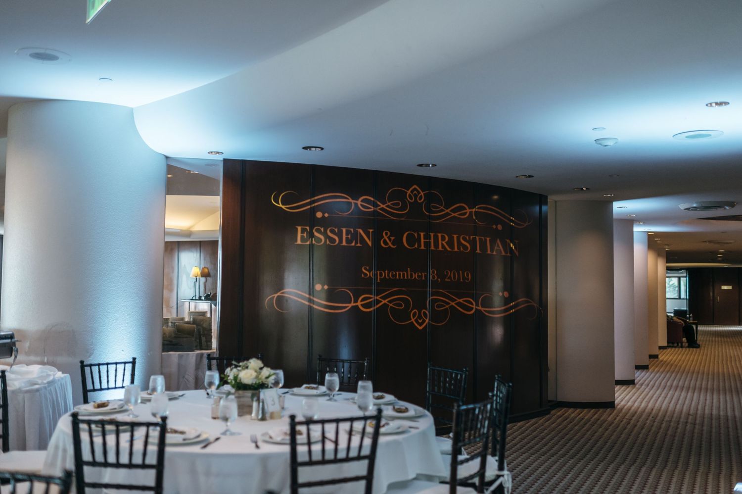 Modern wedding reception venue with elegant white decor and chiavari chairs.