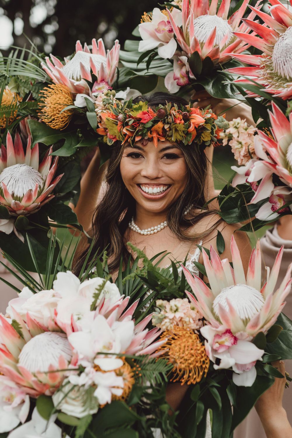 Vibrant pink protea flowers and tropical foliage create a stunning floral crown display.
