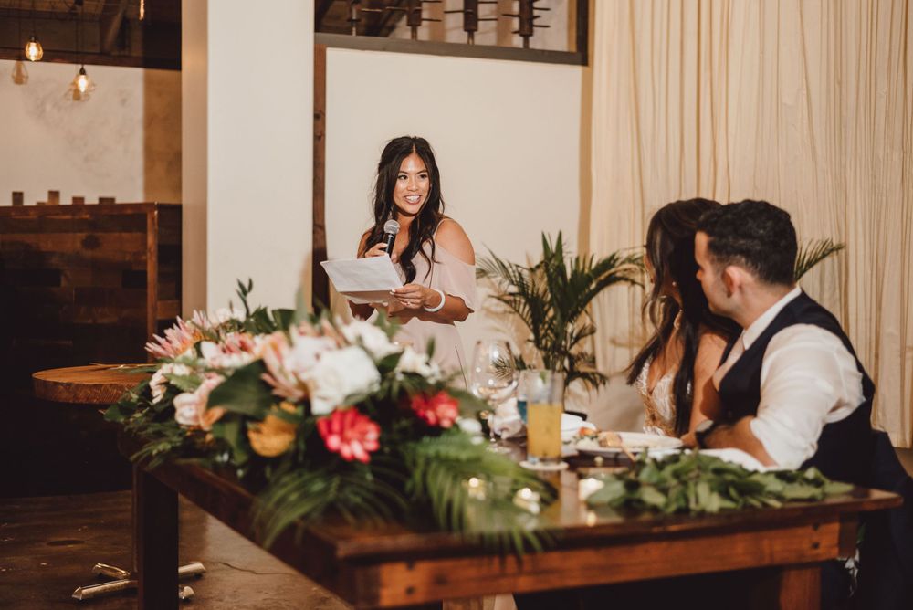 Wedding reception table decorated with floral centerpieces and candles in a rustic indoor venue.