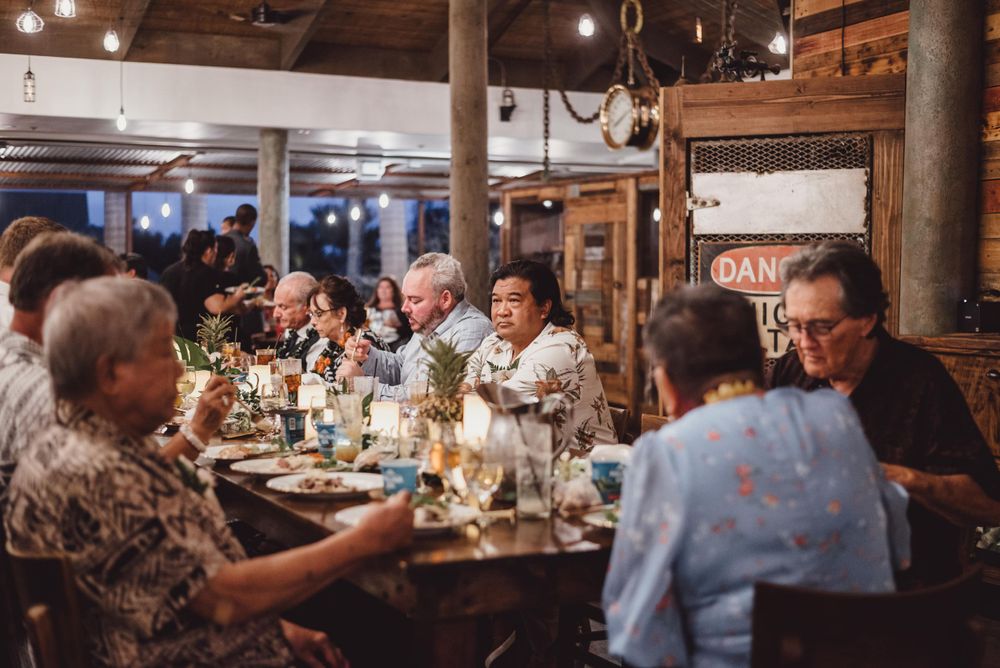 Wedding reception celebration in rustic venue with wooden beams and ambient lighting.