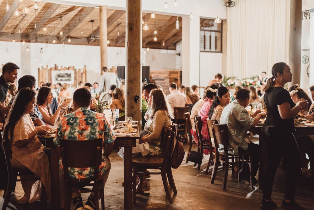 Wedding reception guests mingling in a rustic wooden barn venue with warm lighting.