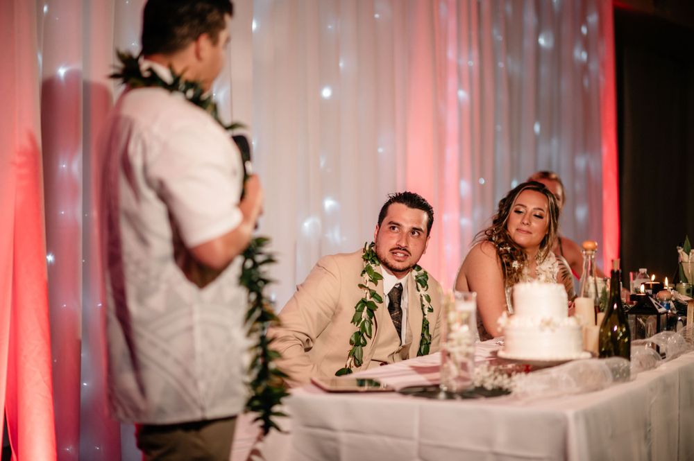 Newlyweds at head table listen intently during wedding reception speeches.