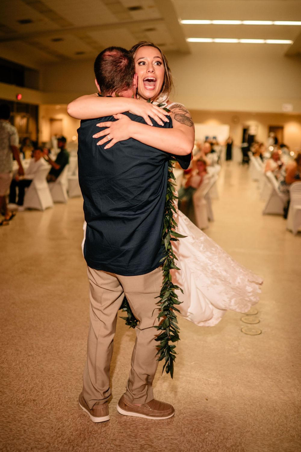 Emotional embrace shared during wedding reception in a decorated banquet hall.