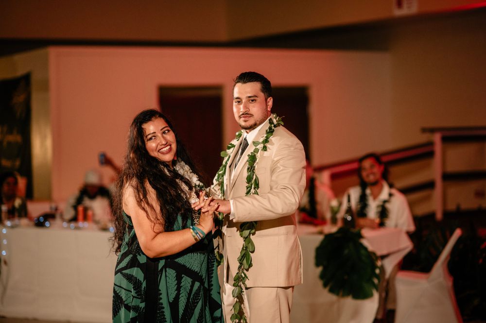 Wedding guests dance together wearing traditional Hawaiian leis during reception celebration.