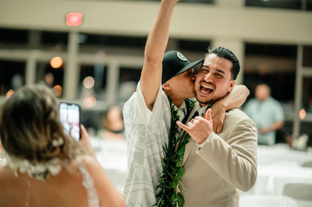 Joyful celebration at a wedding reception with guests wearing traditional Hawaiian leis.